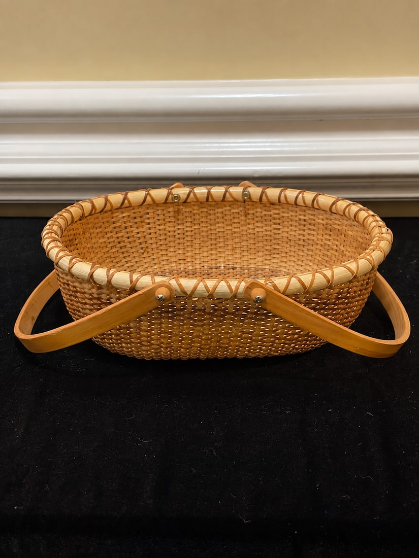 Vintage Nantucket-Style Oval Woven Basket with Swing Handle: "Vintage Nantucket-Style Oval Woven Basket with Swing HandleVintage Nantucket-style oval basket featuring tightly woven cane construction, a solid wooden base, wrapped rim, and wooden swing handle wit
