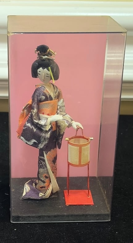 Vintage Japanese Geisha Doll with Lantern in Display Case: "Vintage Japanese Geisha Doll with Lantern in Display CaseVintage Japanese geisha-style doll dressed in a detailed purple and orange patterned textile kimono and posed beside a miniature lantern. Pres
