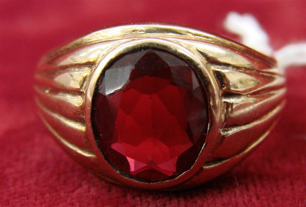 10K Yellow Gold & Ruby Color Stone Mans Ring: 10K Yellow Gold Mans Ring with a Large Oval Ruby Colored Stone. Size 11; 5.7 Grams. Auction Estimate $200-300.