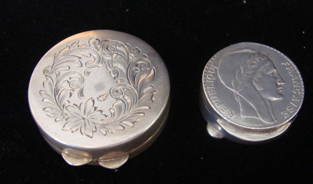 2 Antique Sterling Silver Repousse Pill Boxes: Two Sterling Silver Pill Boxes One with Ten Francs 1938 Coin Design; 1" Diameter and the Other With a Floral Scroll Decor; 1.5" Diameter. TW 40 Grams. Auction Estimate $100-200.