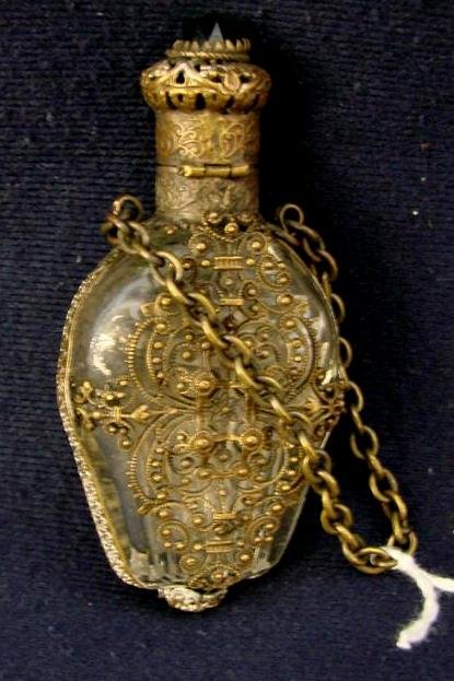19c Victorian Glass Chatelaine Perfume w Brass Fil: Brass and Glass Filigree Jeweled Perfume Chatelaine with a Butterfly on Front with Green Jeweled Wings and Center & matching Jewel in Top. 3" Ht Auction Estimate $50-100.
