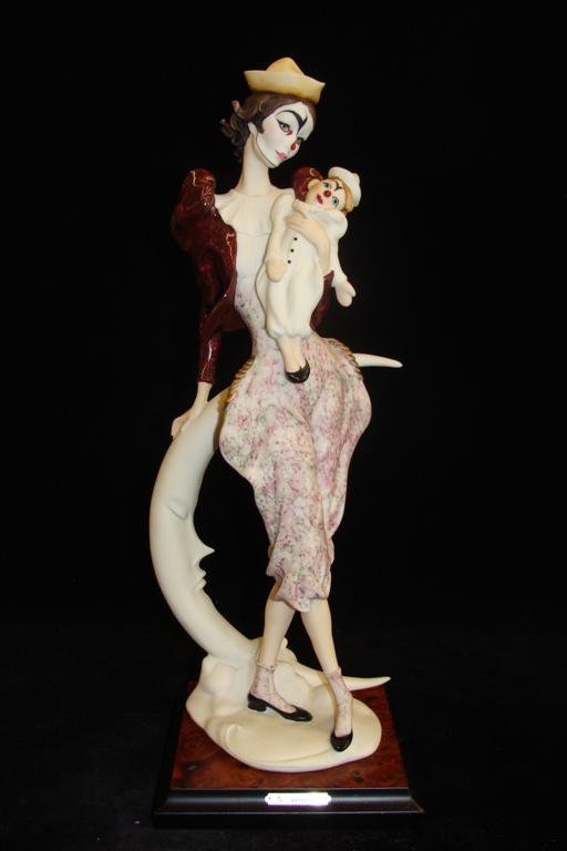 Giuseppe Armani Figurine: Lady Clown with Doll #743C. L: Giuseppe Armani Figurine: Lady Clown with Doll #743C. Ltd Ed #142/7500. Depicts Shy Female Clown Holding a Doll, Leaning on a Crescent Moon. 15" Ht. Auction Estimate: $400-600.