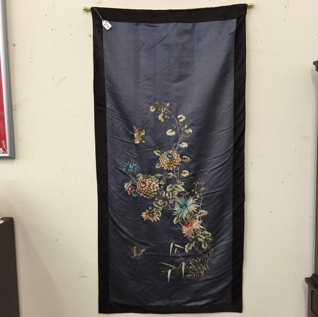 Antique Chinese Needlepoint Silk Tapestry.: Antique Chinese Needlepoint Silk Tapestry Depicting a Vine of Open Florals; Mums, Bird & Butterfly. 57 x 27". Deep Blue Silk Background with Black Border; Note: Some Fraying to Border. Would Be Beauti