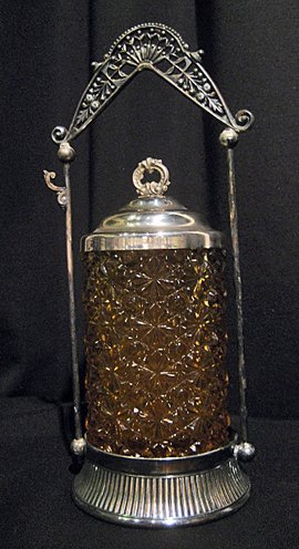 Amber glass pickle caster in silver-plated stand,: Amber glass pickle caster in silver-plated stand, 11" high - handle damaged.