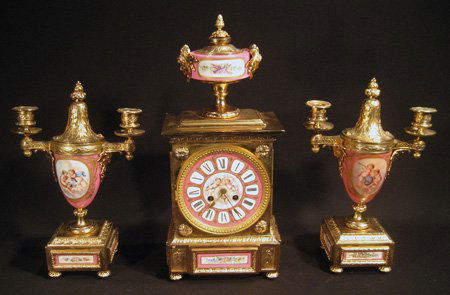 18Kt. gold plated PH Mourey French clock garniture set: 18Kt. gold plated P.H. Mourey French clock garniture set: clock with urn finial, porcelain side panels, 18" high, 8-1/2" wide - glass door detached, needs hinge restoration and pair matching lidded ur