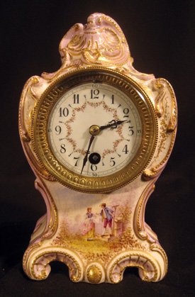 Sevres small porcelain cased dresser clock: Sevres small porcelain cased dresser clock decorated with man and woman in garden, signed Rama, 9" high.