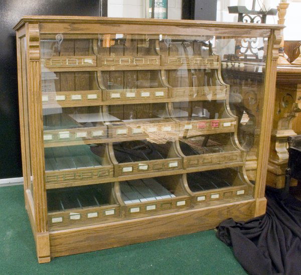 Oak cased candy store display case w/15 small drawers: Oak cased candy store display case with fifteen small drawers with candy labels AGE: Antique SIZE: 41" high, 50" wide