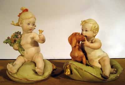 Two Cappe porcelain seated girls on pillows: Two Cappe porcelain seated girls on pillows: one with dog and one with flower bouquet. 3.25" high and 4" high.