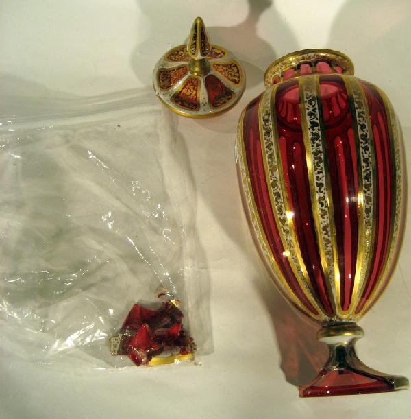 Cranberry Overlay Glass Lidded Urn: Cranberry overlay glass lidded urn with gilded decoration on ribbed design, 15.75" high, 5.75" wide - lid repaired and base heavily damaged. Age: antique.