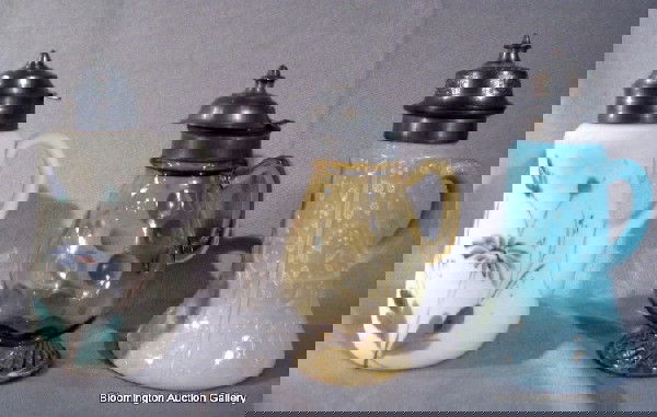 3 Victorian Glass Syrup Pitchers: Challinor & Tayl: Three Victorian glass syrup pitchers: Challinor & Taylor co blue glass "Tree of Life" pattern; amber glass, "Coin Spot" pattern and white satin glass with painted flowers - lids detached on blue glass