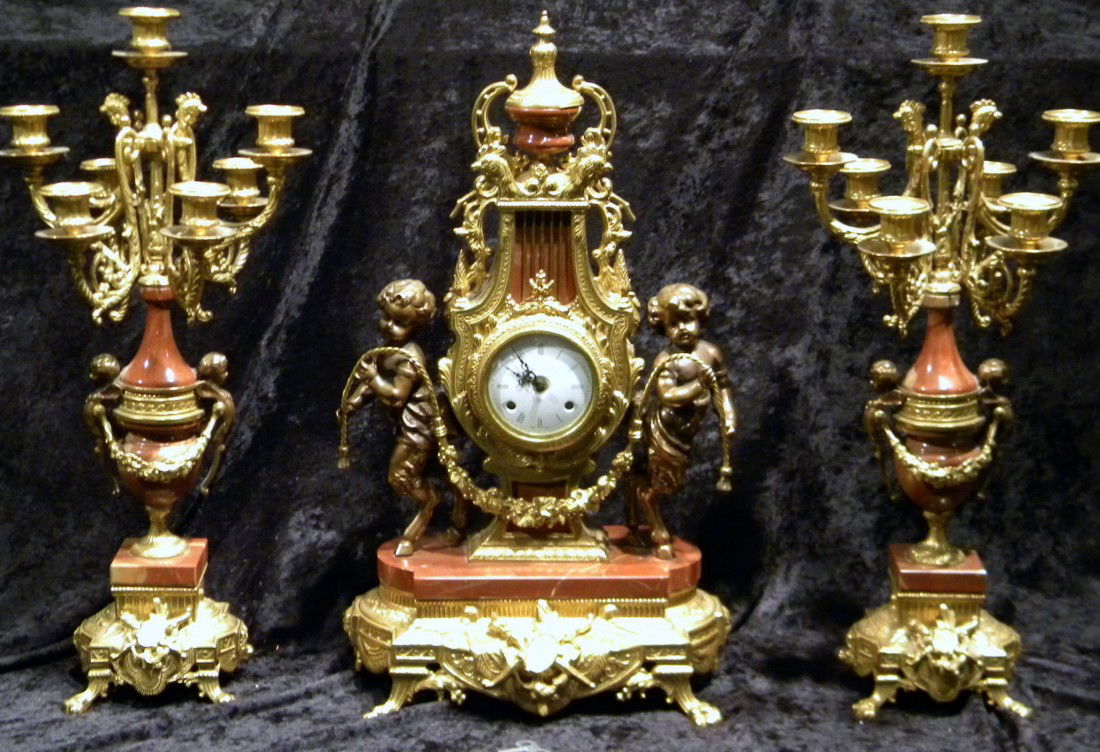 Three Piece Gilt Metal & Marble Clock Garniture Set: Three piece gilt metal and marble clock garniture set, 20th century, dial inscribed "Imperial/MADE IN ITALY". The lyre-form clock flanked by baby satyrs holding a garland, urn-form finial and 4 basili