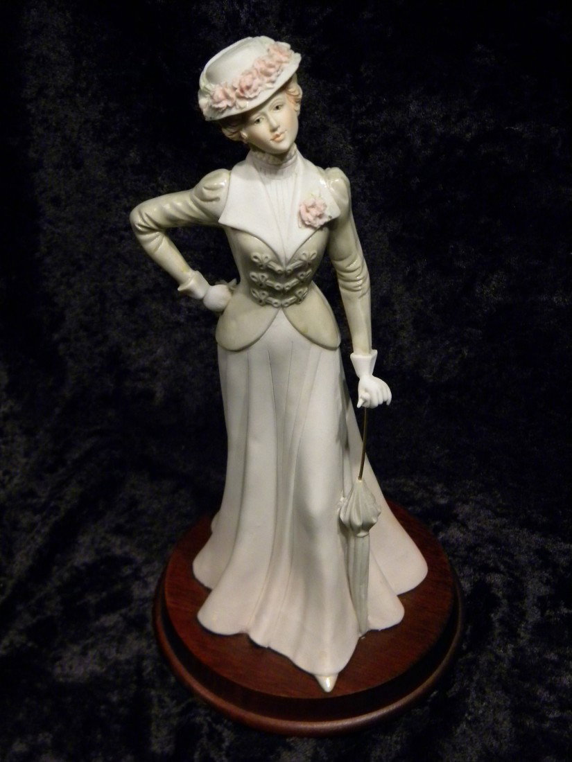 Porcelain Figurine, Woman w/Umbrella, Signed Pucci : Porcelain figurine of woman with umbrella on wooden base, signed Pucci, marked 1984 Arnart on lower skirt, 11" high.
