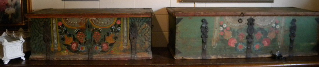 Pair Early Pine Marital Trunks - Bride and Groom: Pair early pine trunks, bride's and groom's, with hand painted decoration and cast iron handles. Groom's: 18.5" high, 61" wide, 23" deep - Bride's: 18" high, 49" wide, 23" deep. Antique. Fair conditio
