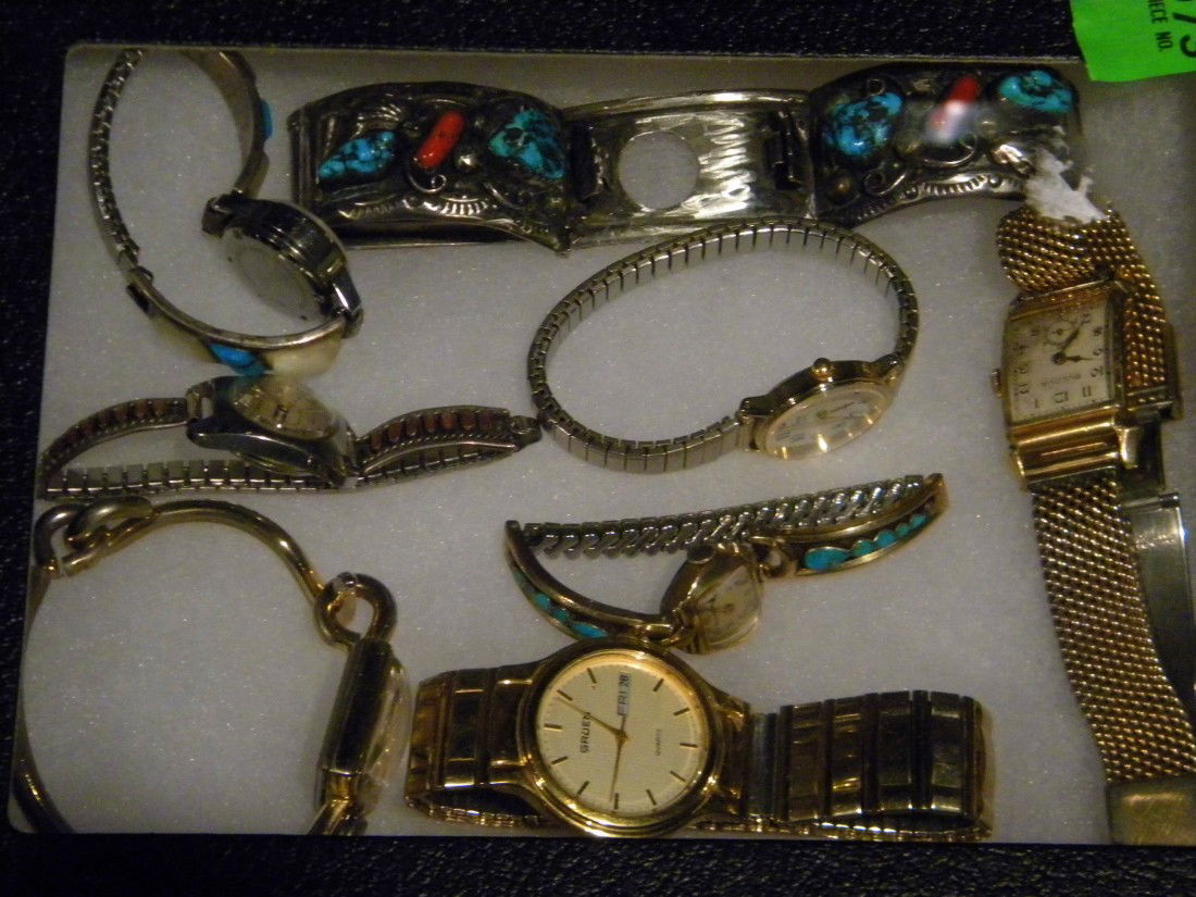 7 Watches & 1 Watch Band in Glass Top Display Case: Collection of 7 watches including: 3 Bulova, Timex, Gruen, Marchel Boucher, Paul Saison and one silver watch band set with turquoise and coral stones in glass top display case.
