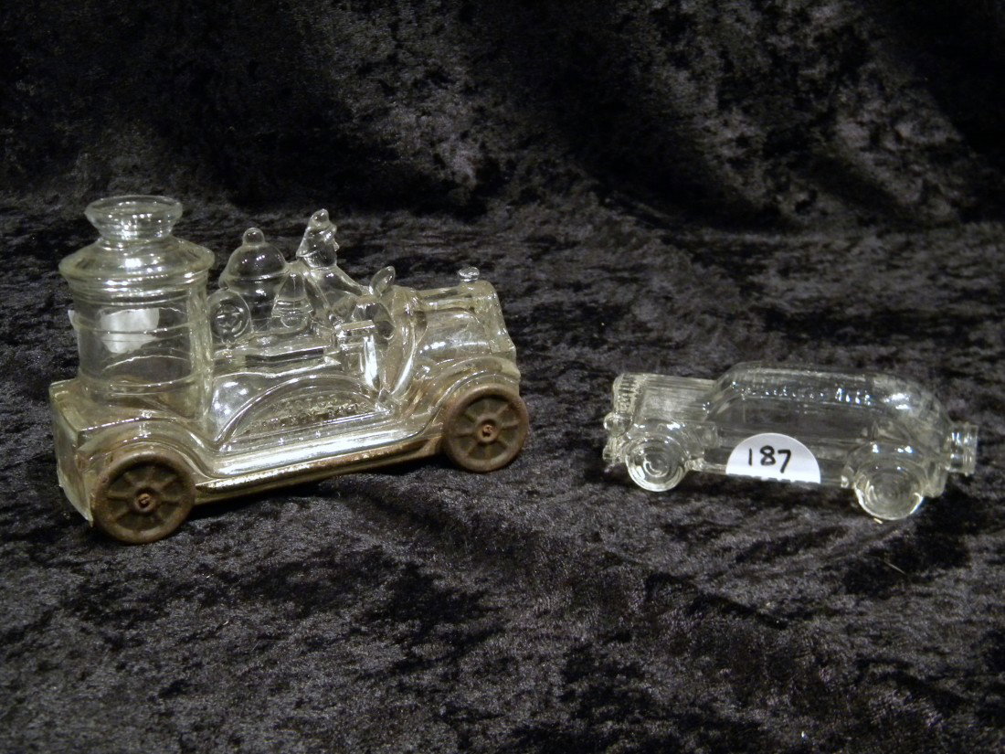 Two Glass Candy Containers: Fire Engine & Wood Car: Two glass candy containers: fire engine with driver "Pat. Nov 24-14", four tin wheels and base cover, 3.5" high, 5" long and woody car, no cap on bottle, 1.5" high, 4" long.