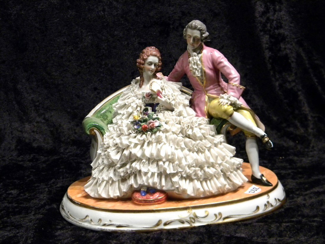 Dresden style porcelain group: man and lady in ornate l: Dresden style porcelain group: man and lady in ornate lace dress seated on loveseat, marked in blue on base under glaze "PMR - (Star) Thuringen, made in Germany", 6.5" high, 9.75" across - foot on man