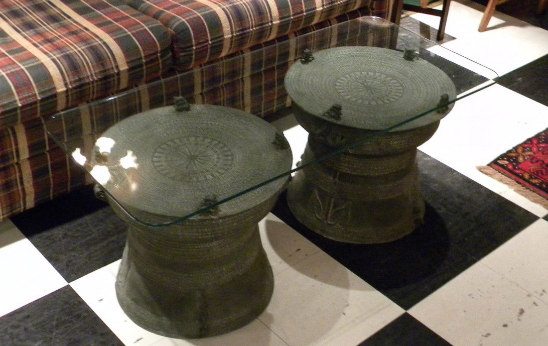 Plate Glass Coffee Table w/Asian Metal Rain Drum Bases: Plate glass coffee table with pair of Asian metal rain drums with green patina - 17" high, top 20" x 44" overall - vintage.