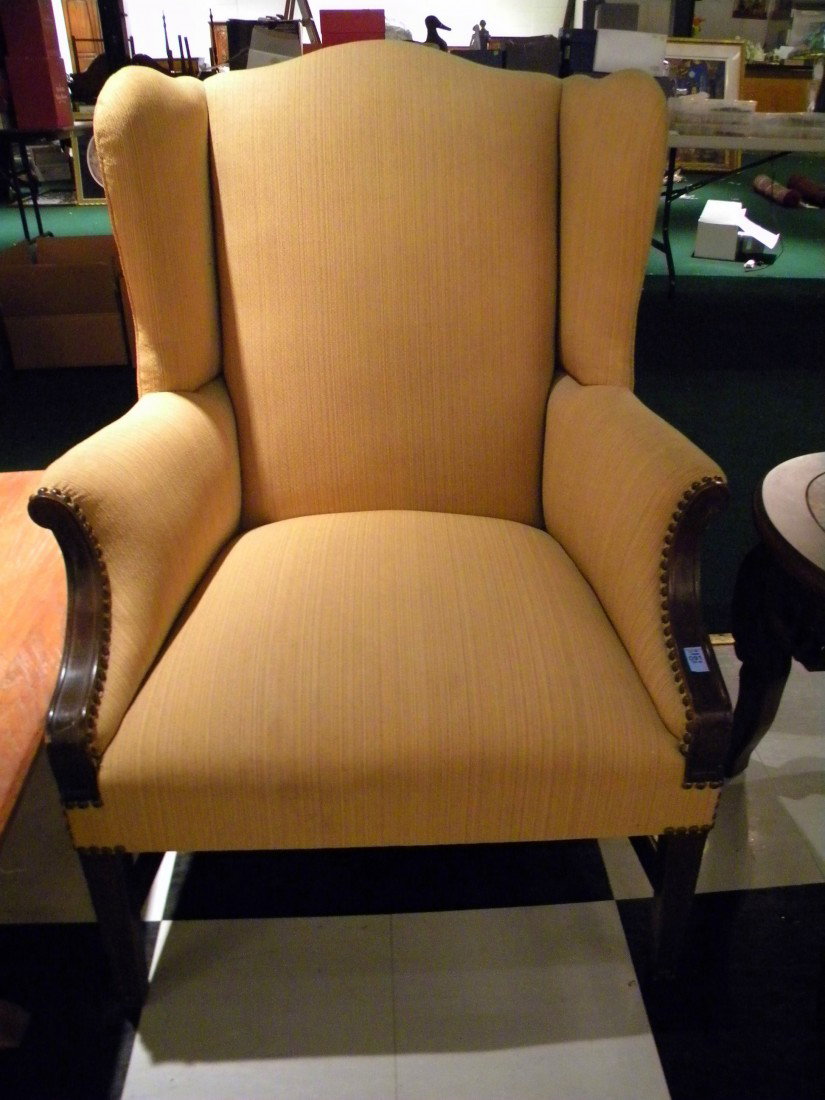 Yellow Upholstered Wingback Arm Chair: Yellow upholstered wingback arm chair with wooden arms and legs, trimmed with brass buttons.