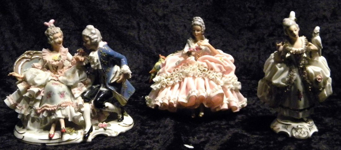 Three Dresden style glazed porcelain figural groups: se: Three Dresden style glazed porcelain figural groups: seated lady on floral couch holding parrot, marked in blue (Crown) N Dresden made in Western Germany, 5.5" high, 6" wide; standing lady in white dr