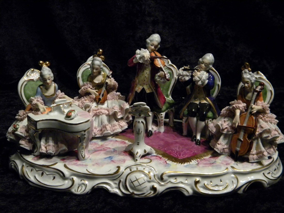 Dresden Style Glazed Porcelain Figural Group: Dresden style glazed porcelain figural music scene: seated woman playing piano, seated woman playing mandolin, standing man playing violin, standing man playing flute and seated woman playing cello, m