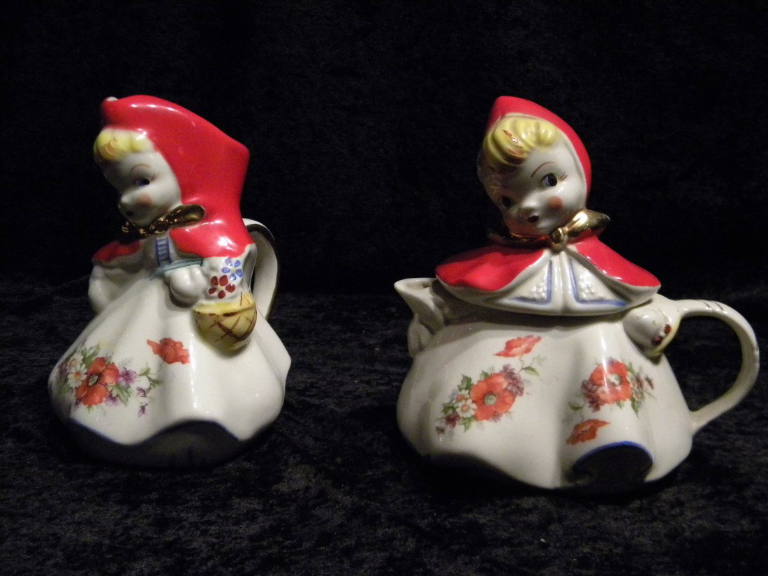 2 Porcelain Little Red Riding Hood Items: Pitcher & Tea: 2 Porcelain Little Red Riding Hood items: pitcher with applied handle, open spout at top of head, unmarked, 8" high, 6.5" wide and lidded teapot with applied handle and spout, marked "USA", 8.5" high,