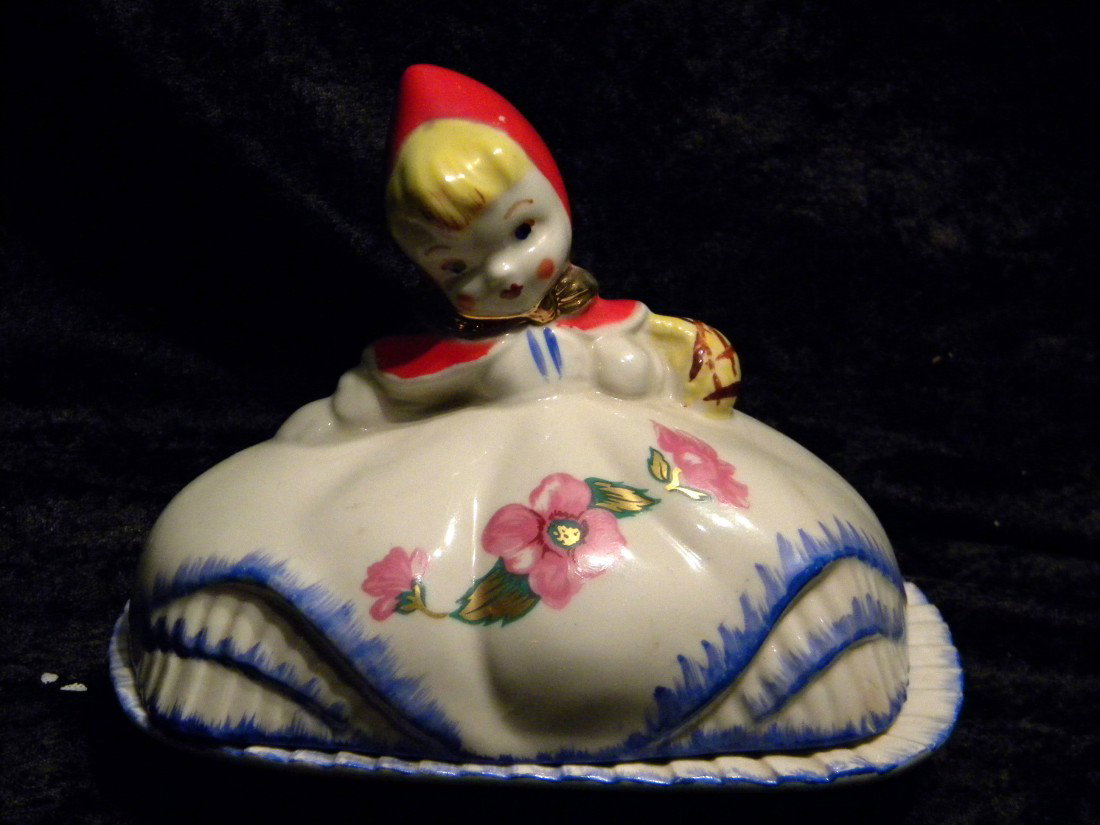 Porcelain Little Red Riding Hood Lidded Butter Dish: Porcelain Little Red Riding Hood lidded butter dish with ruffled skirt and floral decal, marked "Pat Des No 135889", 5" high, 6.5" wide - large repaired crack in lid.