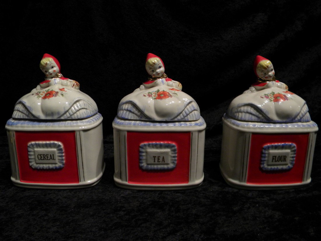 3 Porcelain Little Red Riding Hood Cannisters: 3 Porcelain Little Red Riding Hood lidded canisters: Tea, Cereal and Flour, all decorated with flowers and leaves with figural lids of Red Riding Hood. Marked "Pat. Des No. 135889", 9.5" high, 6.25" w