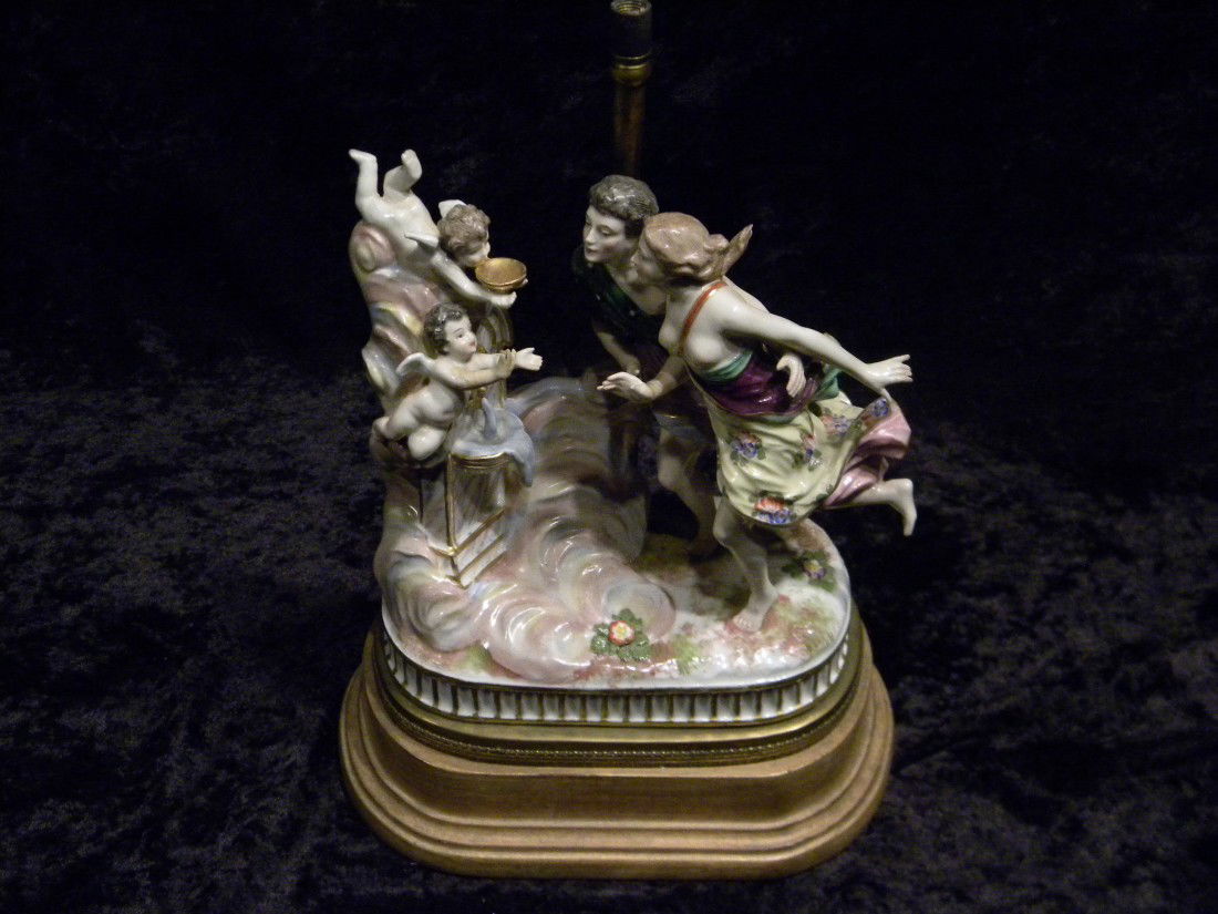 Glazed Porcelain Figural Group: Glazed porcelain figural group: two figures and cherubs - hands repaired, on base, 12" high, 8" wide. (Previously Lamp). Blue crossed sword mark.