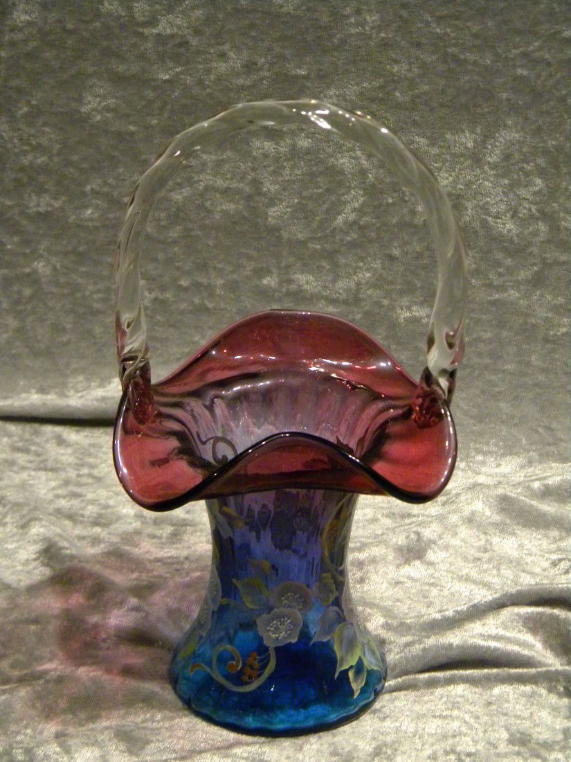 Fenton Glass Basket, Blue, Amethyst, Hand Painted, Sgnd: Blue to amethyst Fenton glass basket with ruffled rim and clear applied handle and hand painted with floral design. Base reads "Hand painted by M. Reynolds M21600A" - 10"h