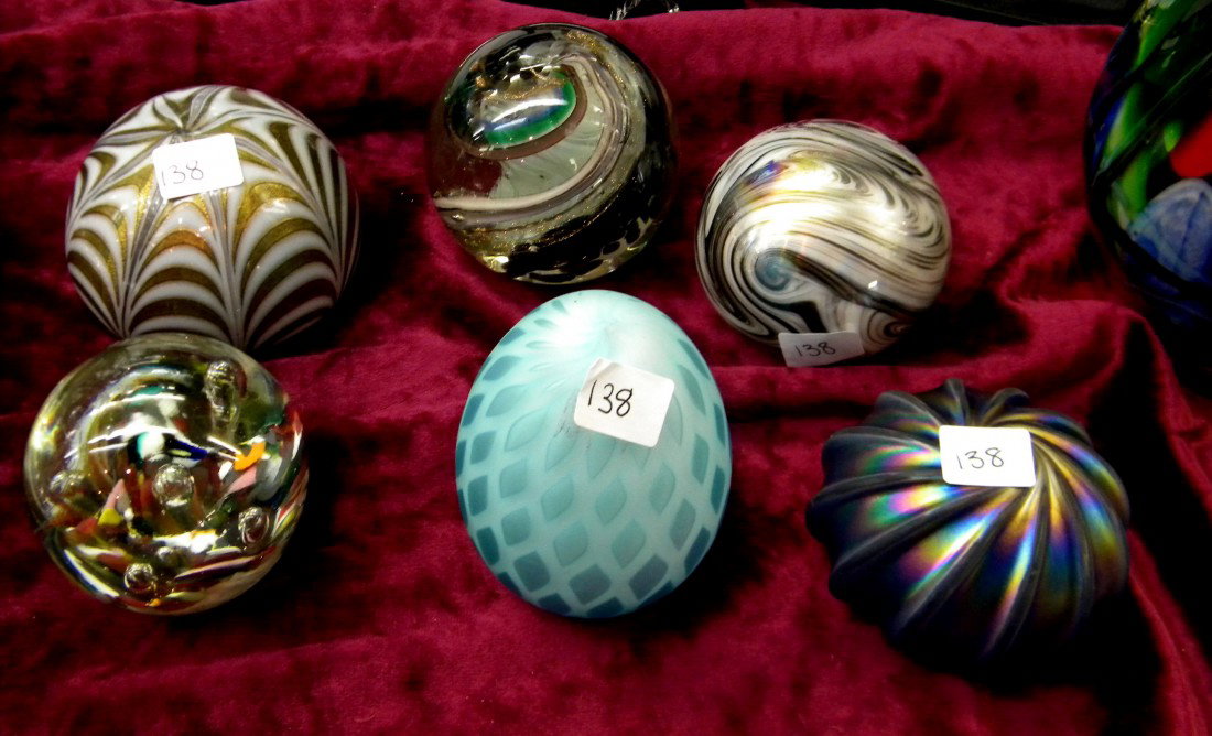 6 Glass Paperweights: 6 Glass paperweights: 2 clear glass with interior flowers (one marked Sam 97), blue satin glass egg, 2 gold/white striped and iridescent purple with swirl design, 2" to 4.5" high.
