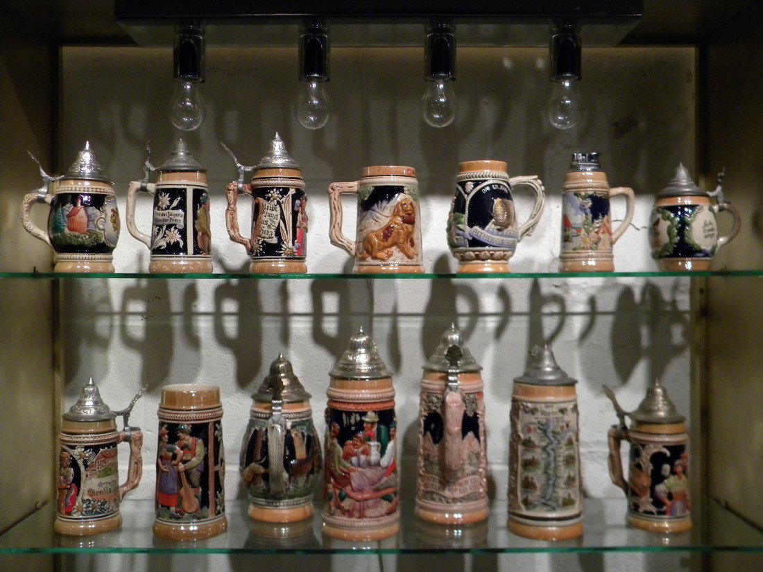 Collection of 14 German Beer Steins & Mugs: Collection of 14 German beer steins and mugs with miscellaneous decorations such as people, animals, flags, towns, etc, ranging from 5" to 10" high.