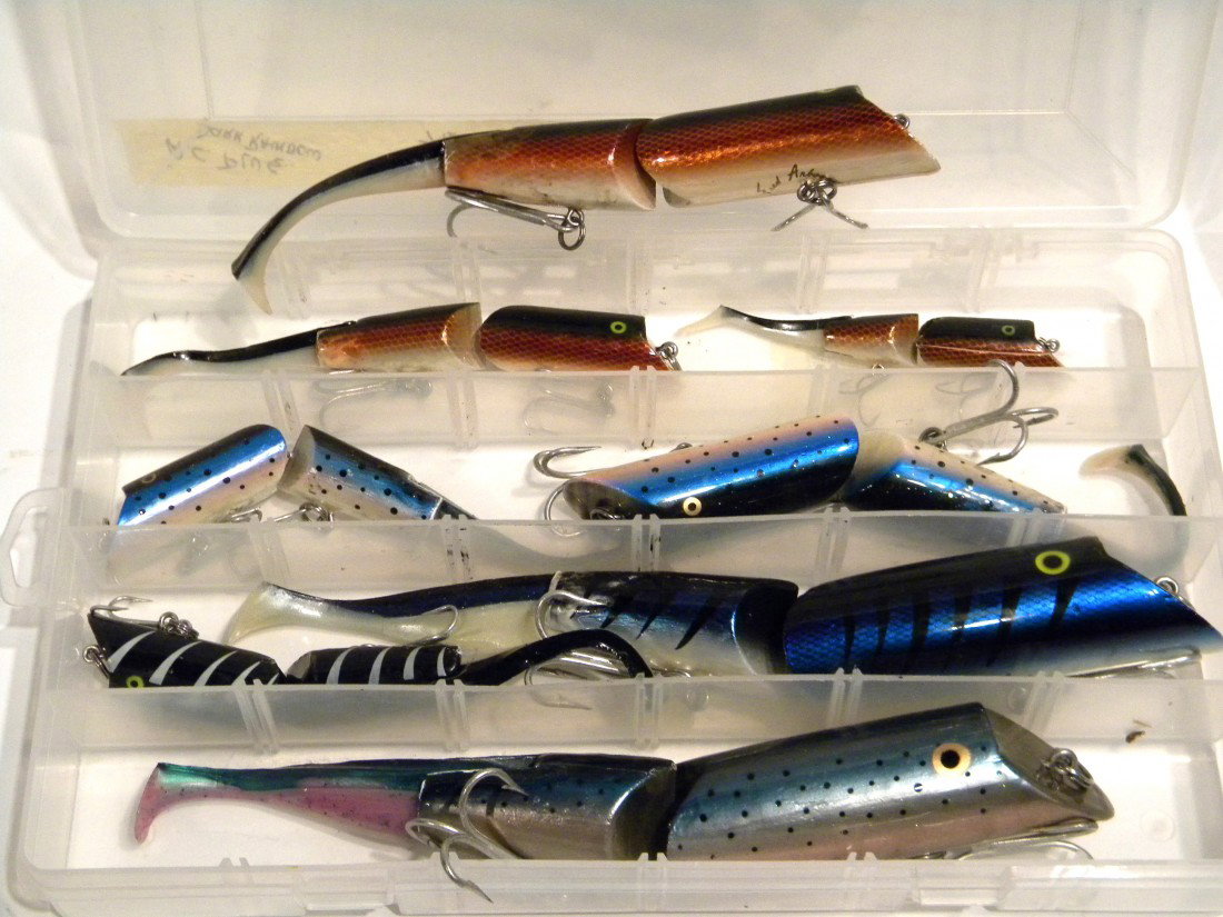 Collection of 8 Double Hook Fred Arbogast Fishing Lures: Collection of 8 double hook Fred Arbogast fishing lures of various colors made out of wood with latex tails, signed on bottom in gold. Sizes range from 5.5" - 11.5" overall.