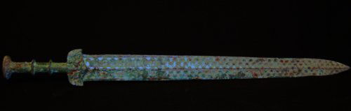 A RARE GILT BRONZE SWORD WARRING STATES PERIOD: The long tapering blade with median ridge and beveled edges, the oval handle encircled by two flanges turquoise with C-scrolls surrounding a quatrefoil motif , with mottled grey and green patina and m