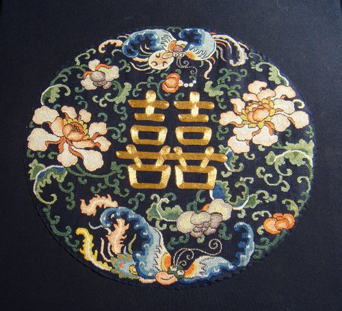 AN EMBROIDERED ROUNDEL FROM A MANCHU NOBLEWOMAN'S : Finely couched in gold-wrapped thread in the center with a shuangxi (Double Happiness) symbol, surrounded by two butterflies and peony scroll bearing lush blossoms, all worked in counted stitch in sha