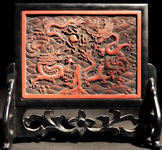 A CINNABAR LACQUER SCREEN QING DYNASTY: A CINNABAR LACQUER SCREEN QING DYNASTY of compressed globular form, well carved through the cinnabar red lacquer with a main circular panel depicting two five-clawed dragons reaching for a 'flaming pe