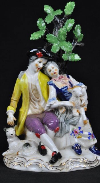 A MEISSEN PORCELAIN FIGURAL MODELED. (1850-1924): A MEISSEN PORCELAIN FIGURAL MODELED. (1850-1924).A couple seated beneath a tree with attendant dog and lamb. Crossed swords mark in blue underglaze, incised ''L144'' impressed "22''. 9 1/2''H.