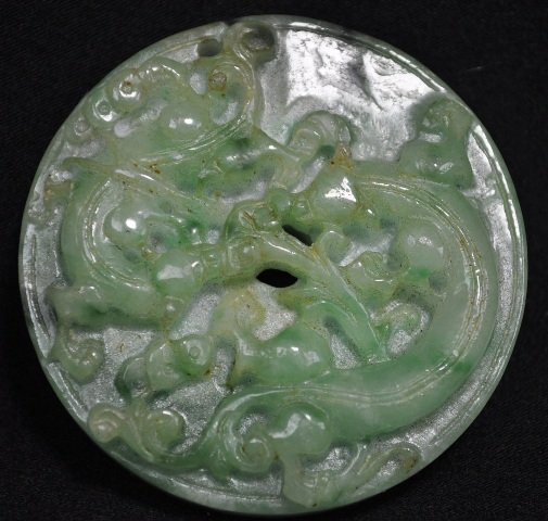 A CHINESE JADEITE BI.(19 CENTURY): A Chinese Jadeite Carving Of Two Dragons Chasing A Ling Zhi.(19 Century) 2 1/8 diam