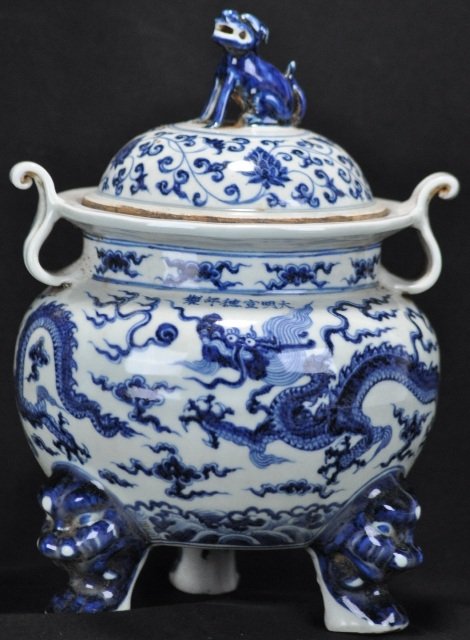 A BLUE AND WHITE JAR.(MARK AND PERIOD OF XUAN DE): A blue and white jar decorated with dragons chasing a pearls and the legs of the jar is lion heads there is a dog standing on the cover.(Mark And Period Of Xuan De) 10''in Tall