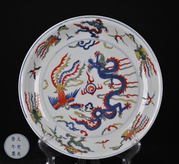 A DOUCAI AND BLUE AND WHITE DISH.(MARK AND PERIOD O: Interior painted with dou cai dragons and phoenixs the exterior painted with blue and white plum and bamboo trees six character mark on the base. 10'' diam