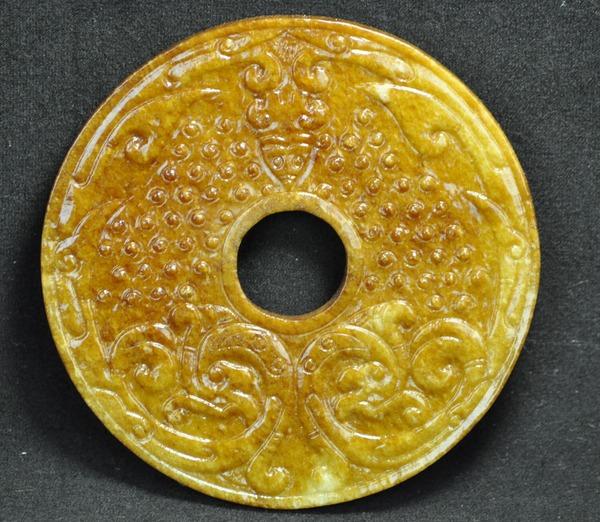 A YELLOW JADE BI.(HAN DYNASTY): Carved dragons and bats. 5'' diam