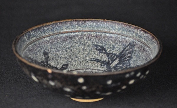 A JIZHOU PAPER-CUT-RESIST DECORATED CONICAL BOWL.(: The interior of the shallow flared sides decorated in resist technique with paper-cut decoration of three floral sprays reserved in brown against the finely variegated, milky buff ground, the exterior