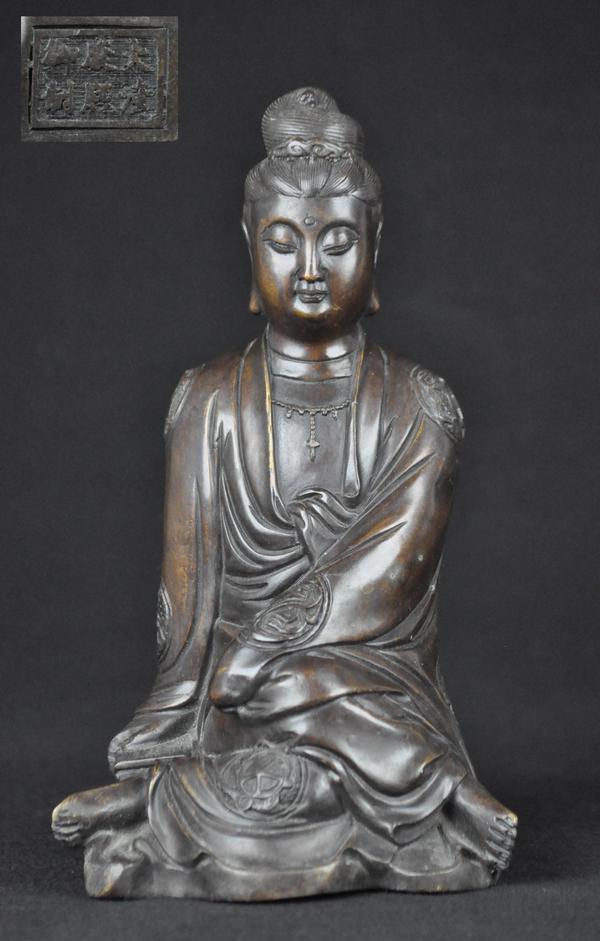A FINELY CAST BRONZE FIGURE OF GUANYIN. (MARK OF K: The elegant figure shown seated with hands hidden within the full sleeves of the gracefully draped robes , and with clouds on the shawl, in the necklace and another forming the urna in the finely cast