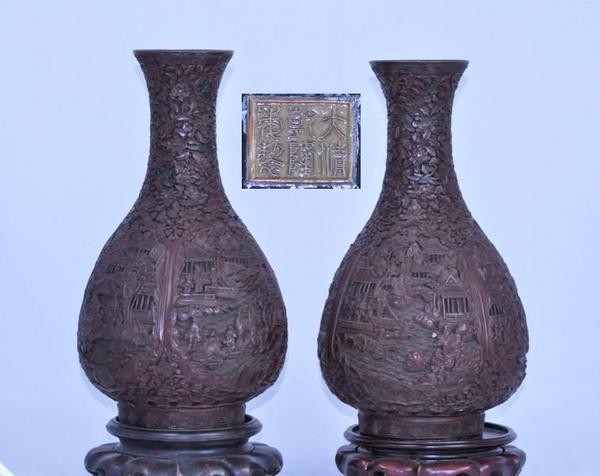 A PAIR OF CHINESE CINNABAR BOTTLE VASES (QING): Well carved with figures in gardens in circular panels on a foliate ground,six character mark on wooden stands 14''Tall PROPERTY FROM A PRIVATE NORTH CALIFORNIA COLLECTION. (Qing Dynasty, 19th Century
