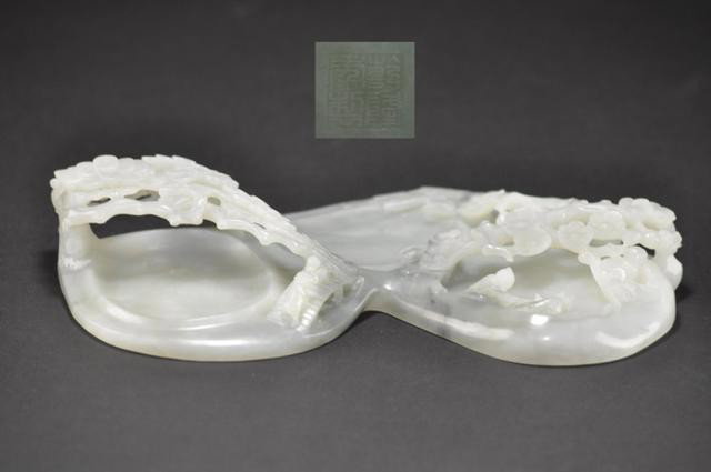 A WHITE JADE CARVING OF BRUSH WASHER.(QING DYNASTY): Carved with landscaping scenes at the base lies a poem with emperior qianlong seal. 10 1/2'' Long PROVENANCE: PURCHASE AT HOGNKONG MARKET AT 1992