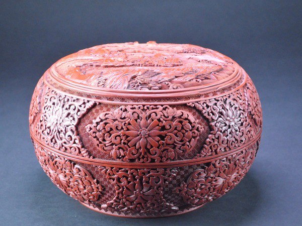 A CINNABAR LACQUER BOX AND COVER. (EARLY 20 CE: A CINNABAR LACQUER BOX AND COVER. (EARLY 20 CENTURY) well carved to the cover with a medallion enclosing eight scholars seated in a garden, the sides and base carved with scrolling flowers and foliage