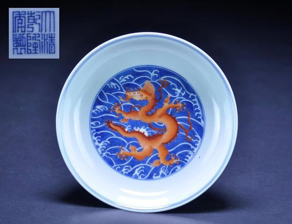 A FINE IRON-RED-DECORATED BLUE AND WHITE 'DRAGON' : A FINE IRON-RED-DECORATED BLUE AND WHITE 'DRAGON' DISH. (MARK AND PERIOD OF QIANLONG) With shallow rounded sides flaring towards the rim, the interior painted in the center with an iron-red dragon lea