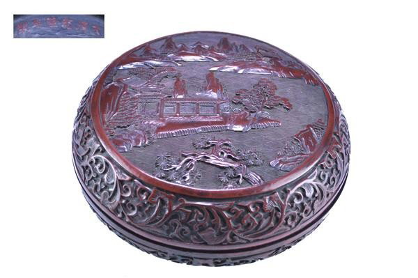 A CHINESE CINNABAR LACQUER CIRCULAR BOX AND COVER,: A CHINESE CINNABAR LACQUER CIRCULAR BOX AND COVER, (QING DYNASTY) carved in relief on the cover with a medallion depicting bearded elders and young attendants gathered beneath pine within a keyfret bo