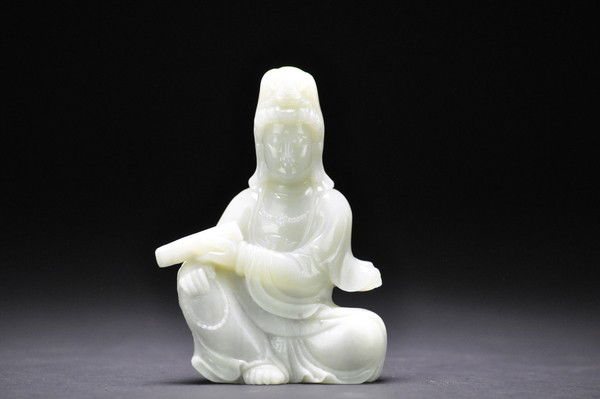 A WHITE JADE CARVING OF GUANYIN.: - A WHITE JADE CARVING OF GUANYIN. wearing flowing robes and a necklace, seated in Royal ease her left hand holding a scroll,with her arm resting on her right foot.14 cm H