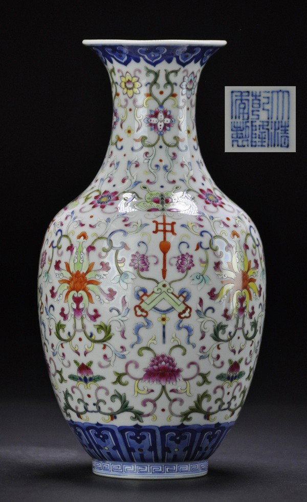 A FAMILLE-ROSE VASE.(MARK OF QIANLONG UNDERGLAZED : - A FAMILLE-ROSE VASE.(MARK OF QIANLONG UNDERGLAZED IN BLUE) densely decorated with an opulent design comprising four primary lotus blooms beneath stylised bats, Buddhist emblems and the san duo motif