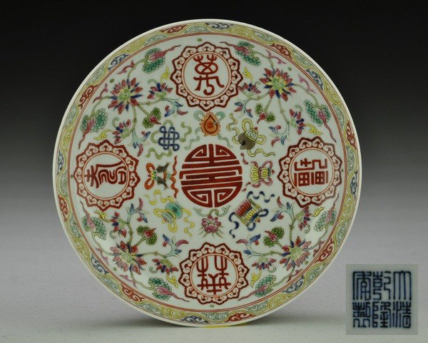 A FAMILLE-ROSE DISH.(MARK OF QIANLONG): The interior painted with BaJiXiang symbol surrounding a Shou character and exterior with bats design, six character mark on base. 1 1/2''H 7 1/2''Diam